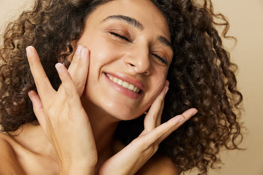 Mujer sonriente aplicando gel con vitamina c en el rostro